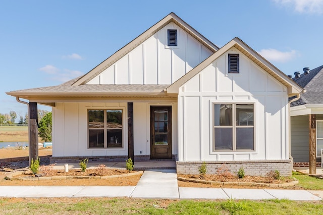 modern farmhouse style home featuring a porch, board and batten siding, and roof with shingles