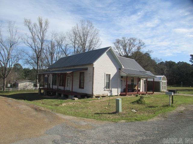 410 E Magnolia St, Rison, AR 71665 - view of home's exterior featuring an outbuilding, a yard, a storage shed, covered porch, and metal roof