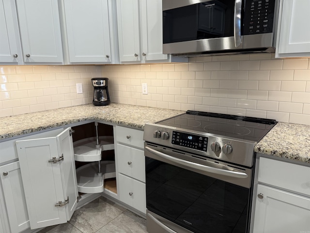 kitchen featuring light stone counters, decorative backsplash, light tile patterned floors, appliances with stainless steel finishes, and white cabinets