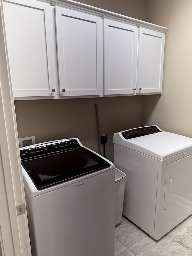 clothes washing area with washer and dryer and cabinet space