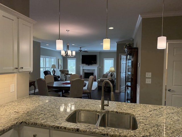 kitchen featuring a sink, tasteful backsplash, a healthy amount of sunlight, and a high end fireplace