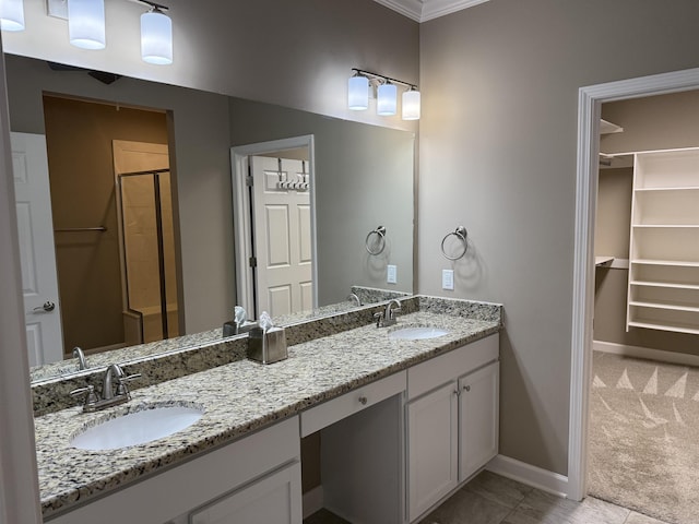 bathroom featuring a shower stall, double vanity, baseboards, and a sink