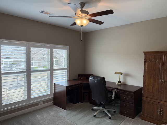 office space featuring light carpet, visible vents, and a ceiling fan