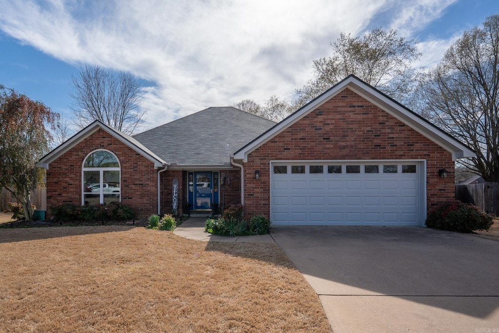 view of front facade featuring concrete driveway, a front yard, a shingled roof, a garage, and brick siding