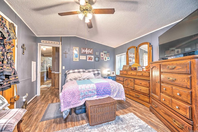 bedroom with a textured ceiling, wood finished floors, crown molding, and vaulted ceiling