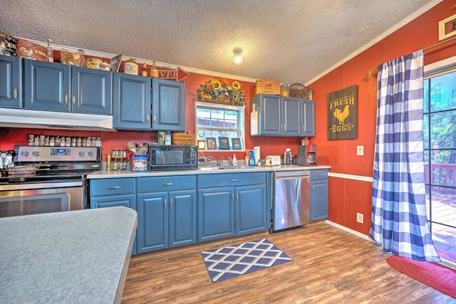 kitchen with under cabinet range hood, appliances with stainless steel finishes, light countertops, and blue cabinets