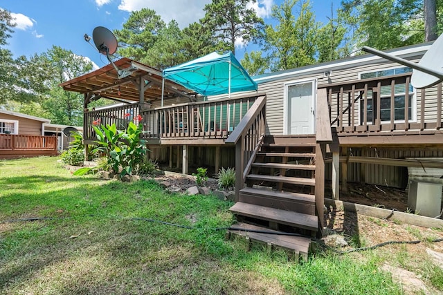 back of property featuring a deck, a yard, and stairs