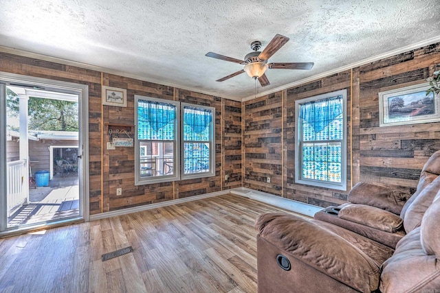unfurnished room featuring visible vents, ornamental molding, a textured ceiling, wood finished floors, and ceiling fan