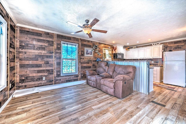 unfurnished living room with a textured ceiling, crown molding, a ceiling fan, and light wood finished floors