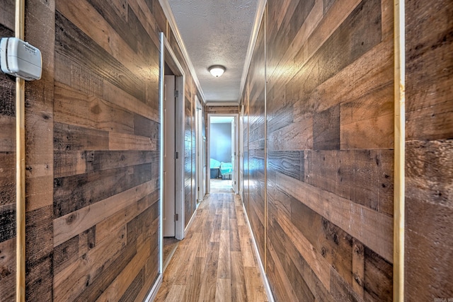 hall with a textured ceiling and wood finished floors