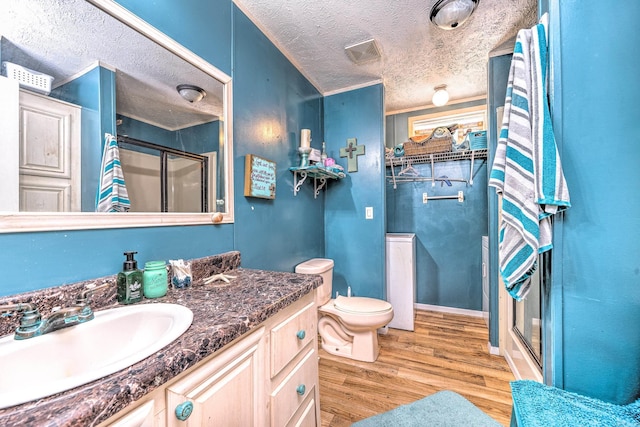 bathroom featuring vanity, wood finished floors, visible vents, a shower stall, and a textured ceiling