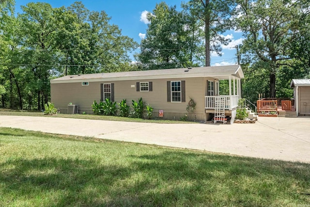 view of front of home with a deck, cooling unit, driveway, and a front yard