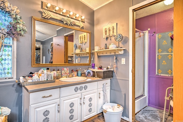 full bathroom featuring enclosed tub / shower combo, a textured ceiling, and vanity