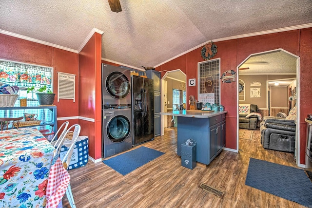 washroom with wood finished floors, arched walkways, stacked washer / drying machine, and ornamental molding