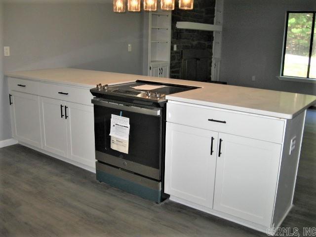 kitchen with dark wood-type flooring, range with electric stovetop, light countertops, and white cabinetry