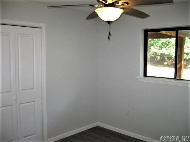 unfurnished room with ceiling fan, baseboards, and dark wood-style flooring