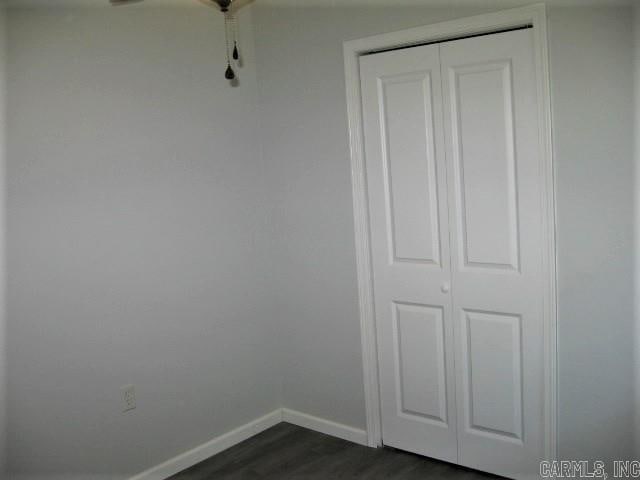interior space featuring a ceiling fan, baseboards, and dark wood-style flooring