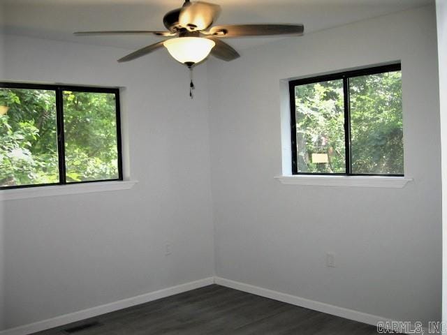 unfurnished room with baseboards, dark wood-type flooring, and a ceiling fan