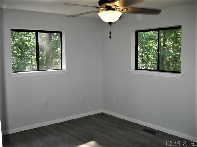 unfurnished room with visible vents, baseboards, ceiling fan, and dark wood-style flooring