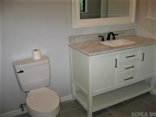 bathroom with tile patterned flooring, toilet, vanity, and baseboards