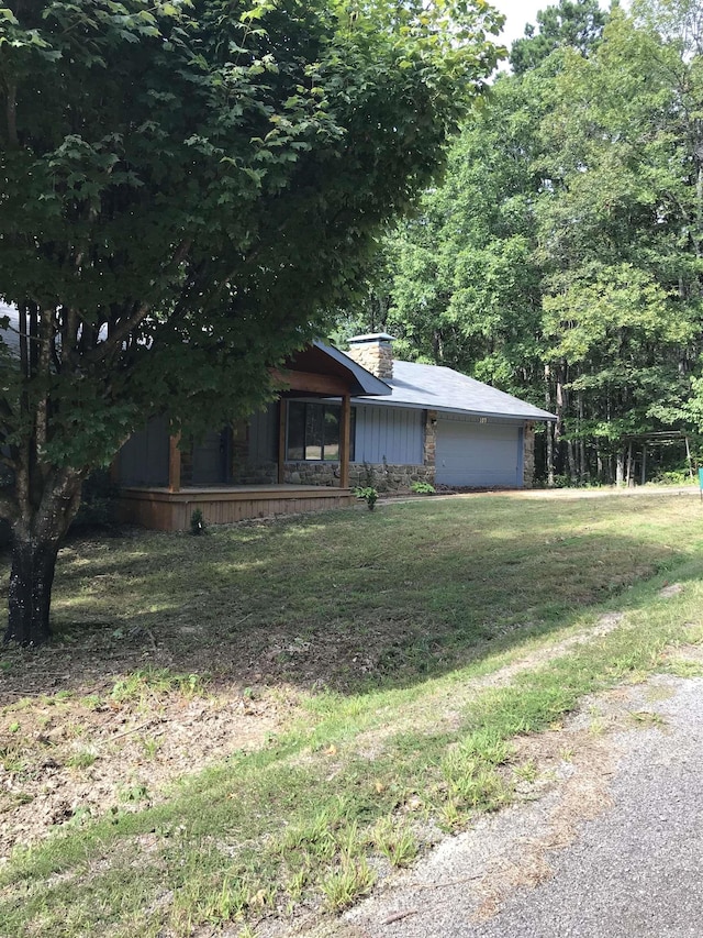 view of front of house with a front yard, a garage, and a chimney