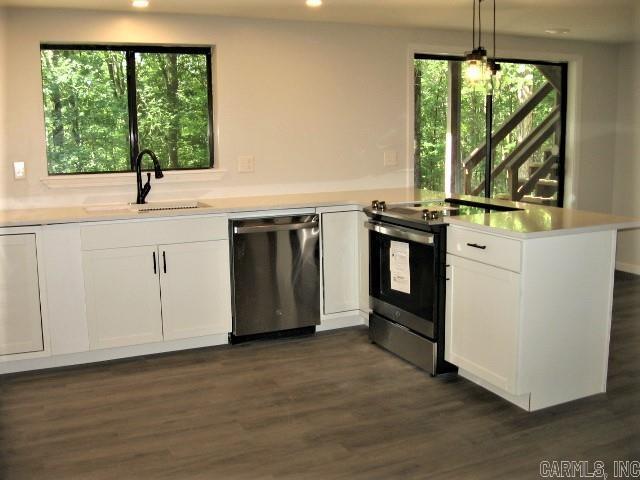 kitchen featuring light countertops, a peninsula, stainless steel appliances, white cabinetry, and a sink