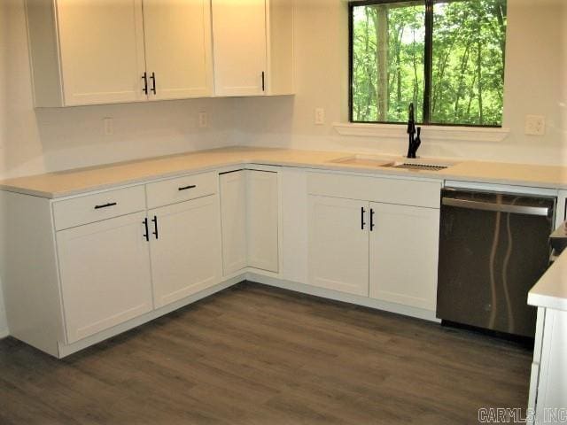 kitchen featuring stainless steel dishwasher, light countertops, white cabinetry, and a sink