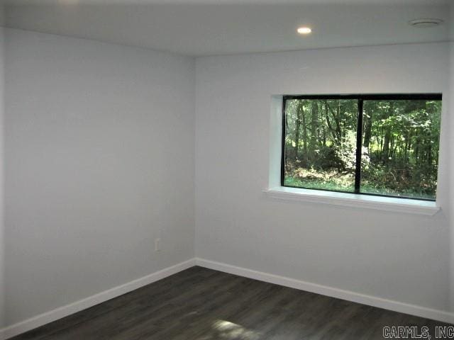 empty room featuring recessed lighting, dark wood-type flooring, and baseboards