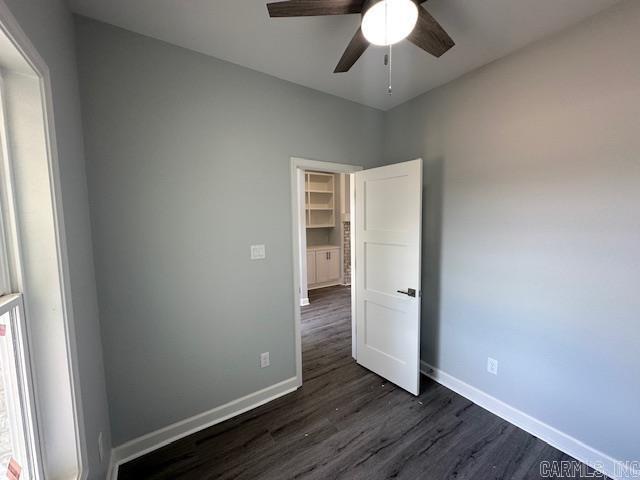 unfurnished bedroom featuring baseboards, ceiling fan, and dark wood-style flooring
