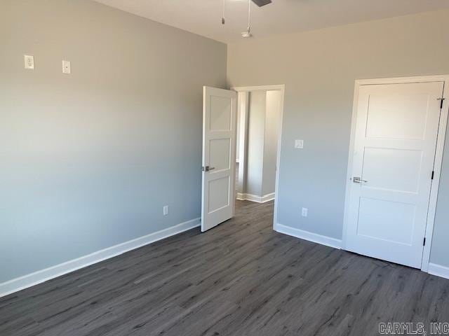 unfurnished bedroom featuring baseboards and dark wood-type flooring