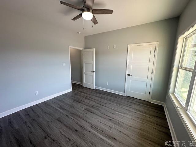 unfurnished bedroom featuring ceiling fan, baseboards, and dark wood-style flooring