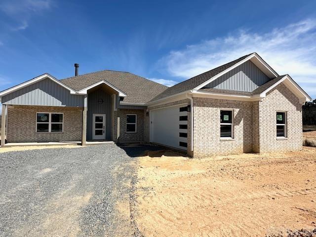 view of front of house featuring brick siding, board and batten siding, driveway, and a garage