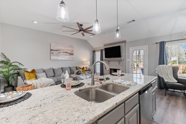 kitchen with visible vents, a sink, light stone countertops, open floor plan, and stainless steel dishwasher
