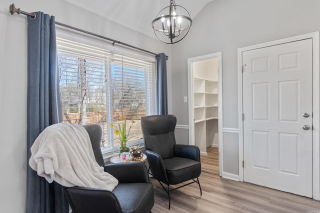 sitting room with a wealth of natural light, baseboards, wood finished floors, and a chandelier