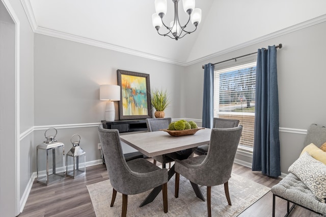 dining space with wood finished floors, baseboards, vaulted ceiling, crown molding, and a notable chandelier