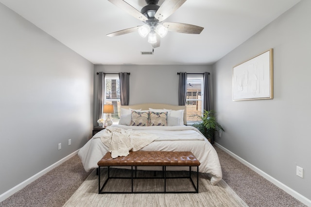 carpeted bedroom with visible vents, baseboards, and a ceiling fan