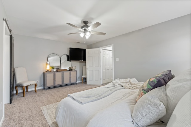 bedroom featuring a barn door, carpet floors, baseboards, and ceiling fan