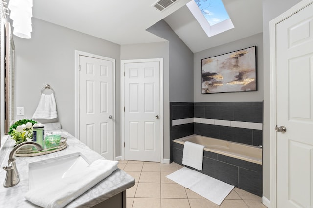 bathroom with vanity, a garden tub, visible vents, vaulted ceiling with skylight, and tile patterned floors