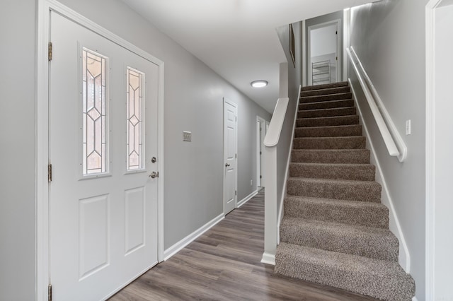 foyer featuring baseboards, wood finished floors, and stairs