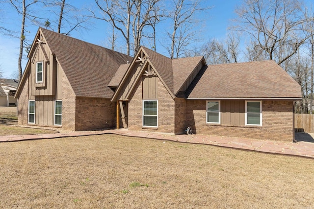 rear view of property featuring brick siding, a lawn, board and batten siding, and a shingled roof