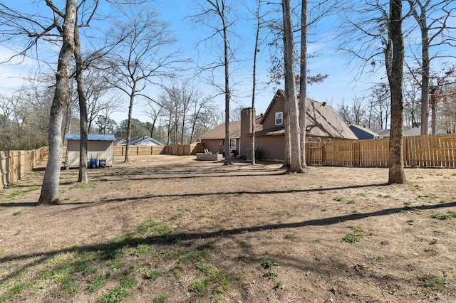 view of yard featuring an outbuilding, a fenced backyard, and a shed