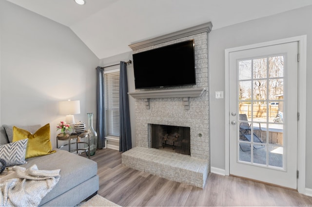 living area with a fireplace, wood finished floors, baseboards, and vaulted ceiling