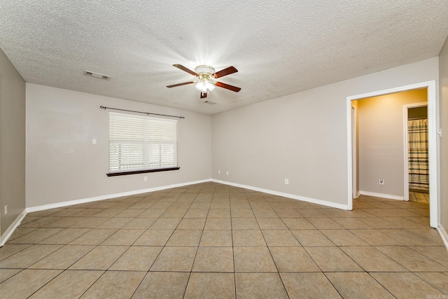 empty room featuring light tile patterned floors, visible vents, baseboards, and a ceiling fan