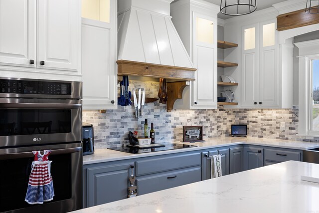kitchen with glass insert cabinets, double oven, custom range hood, white cabinetry, and open shelves