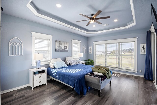 bedroom featuring dark wood finished floors, a raised ceiling, and baseboards