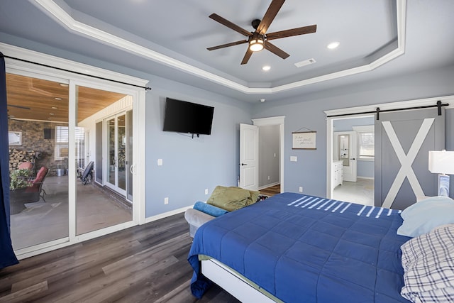 bedroom with a barn door, a raised ceiling, visible vents, and access to outside