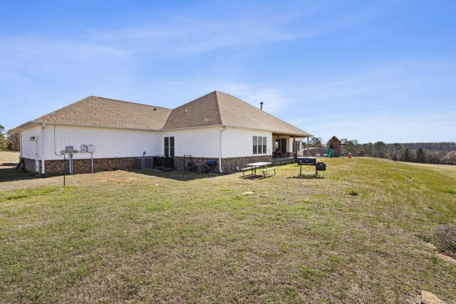 back of house with a lawn and a shingled roof