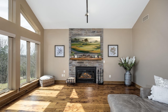 living area with visible vents, vaulted ceiling, plenty of natural light, and hardwood / wood-style flooring