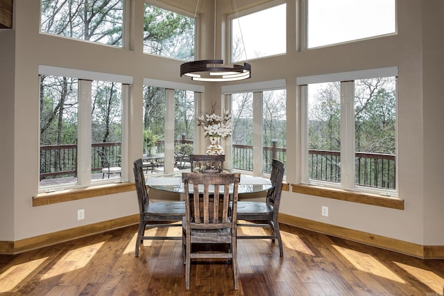 sunroom / solarium featuring baseboards, plenty of natural light, and a towering ceiling
