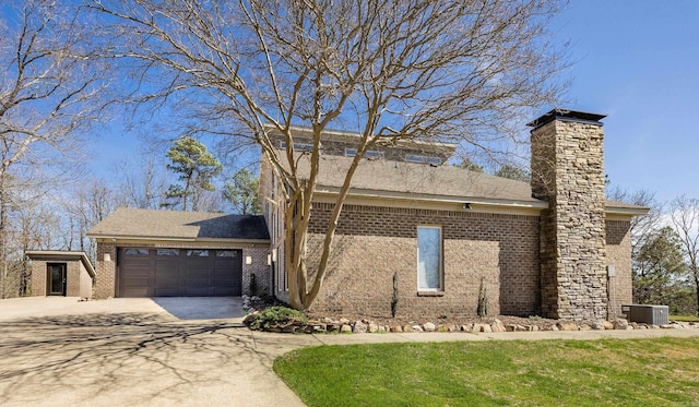 view of front of home featuring a chimney, driveway, cooling unit, brick siding, and a garage